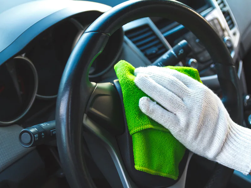 close up of a car detailing contractors hand using a towel to wipe a cars dash buffalo ny
